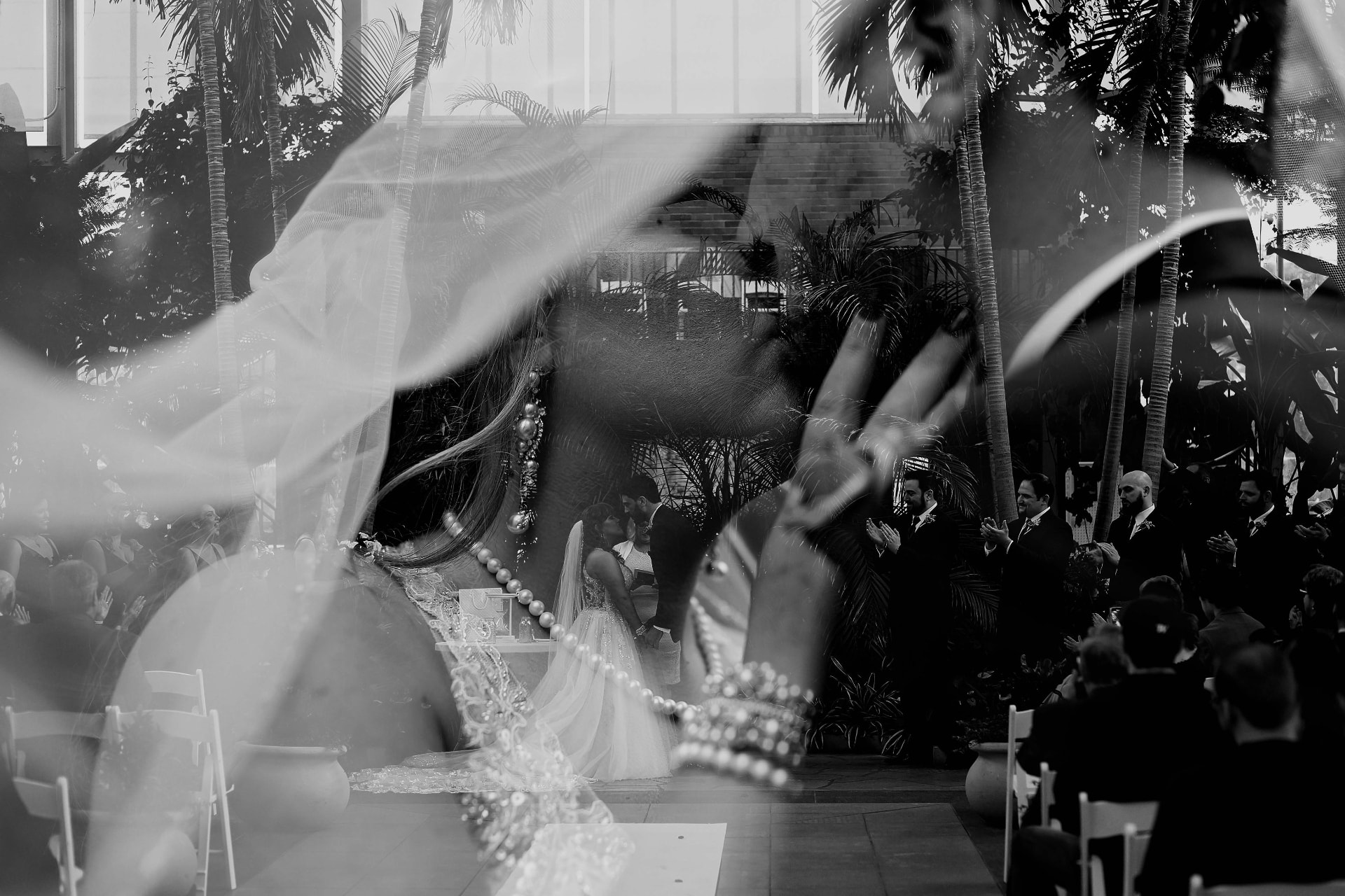 Bride and groom at the altar in a glass conservatory, layered with a portrait of the bride in a flowing veil