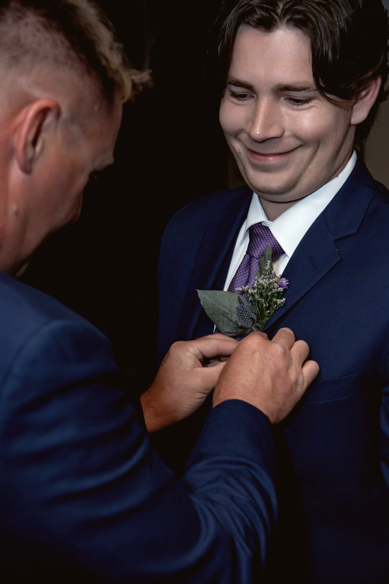 Father pinning a boutonniere on the groom
