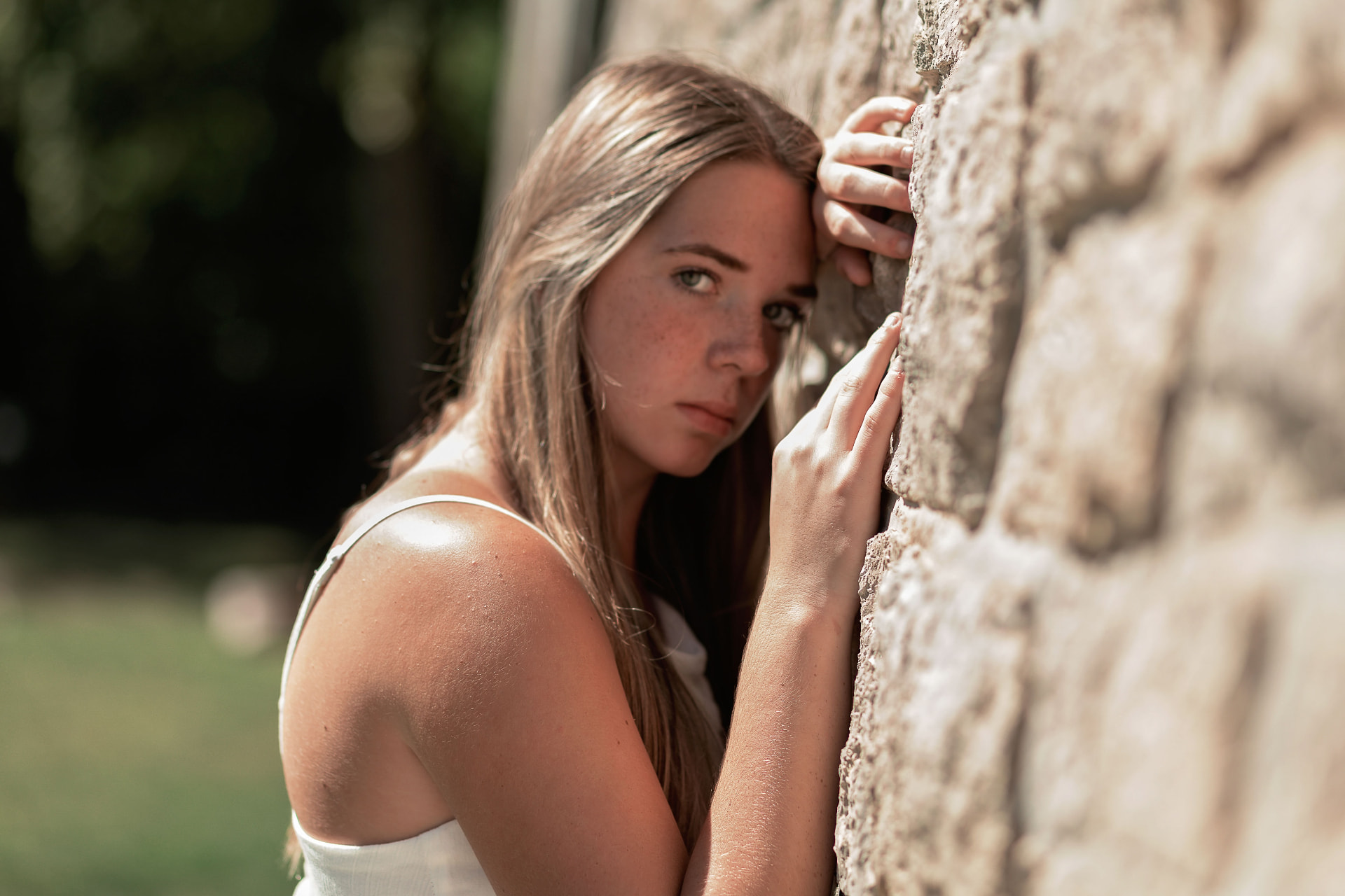 Senior leaning against a stone wall in late sun
