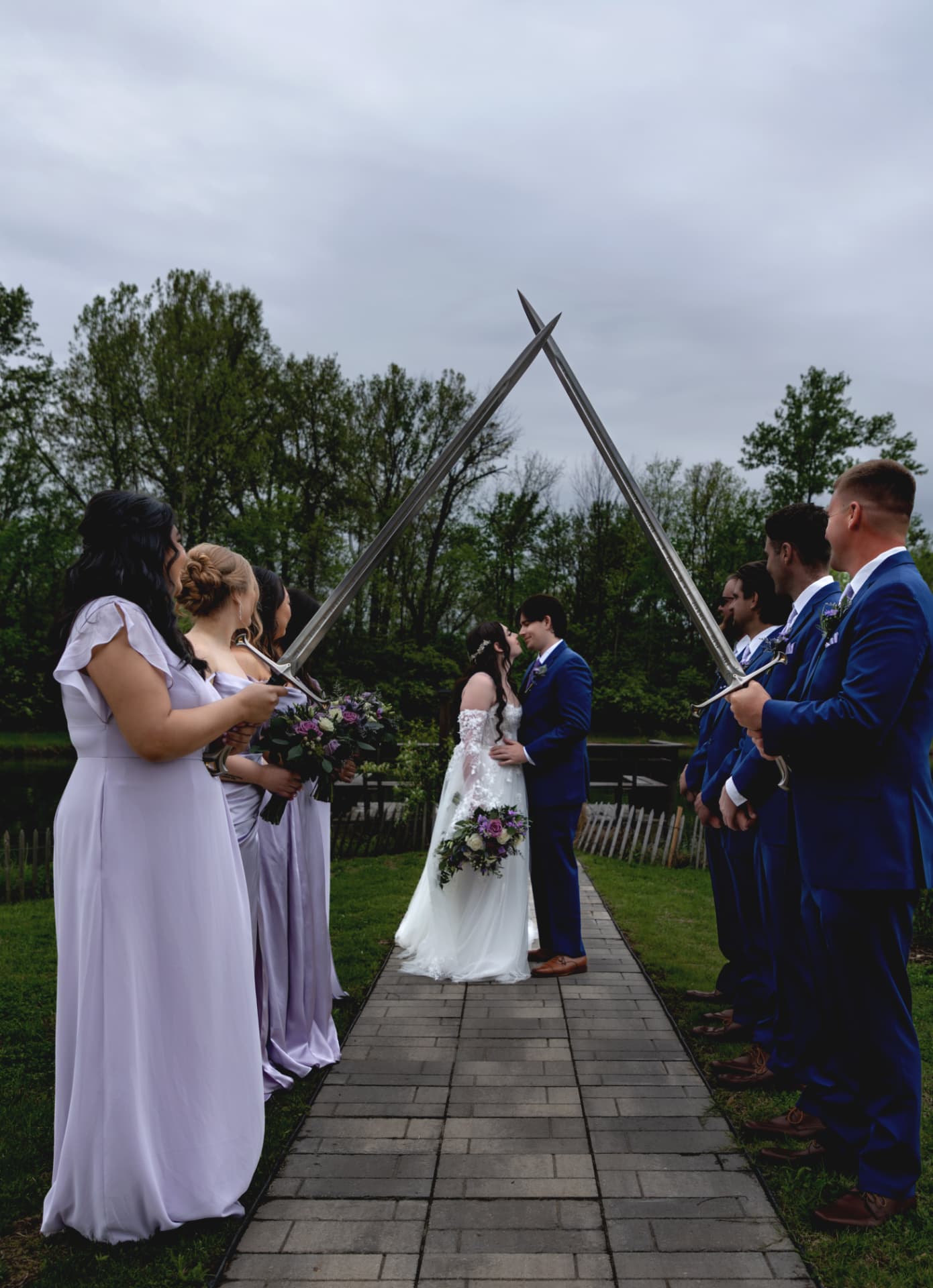 Wedding party gathered outdoors with purple bouquets