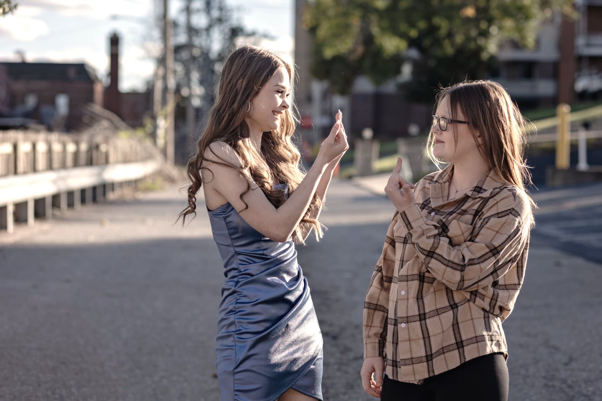 Two sisters laughing together on a quiet street