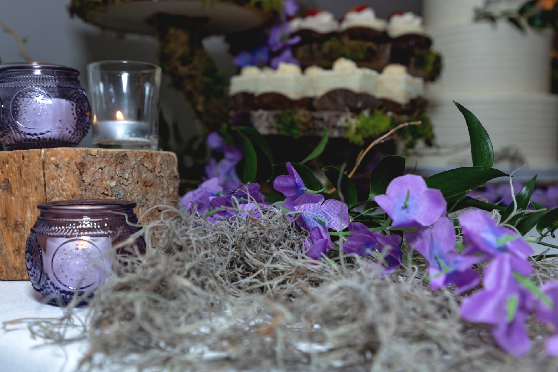 Purple floral centerpiece beside candles