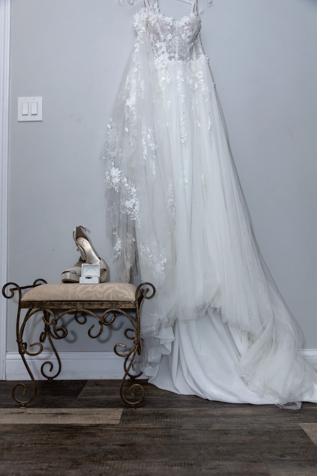 Wedding gown hanging beside bridal shoes