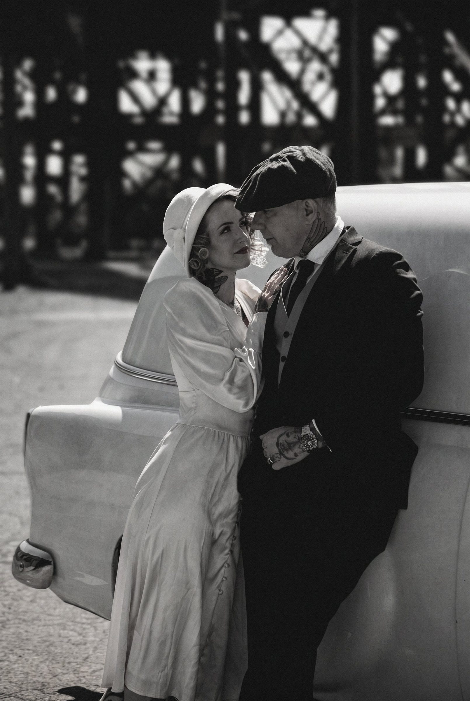 Bride and groom beside a vintage car in black and white