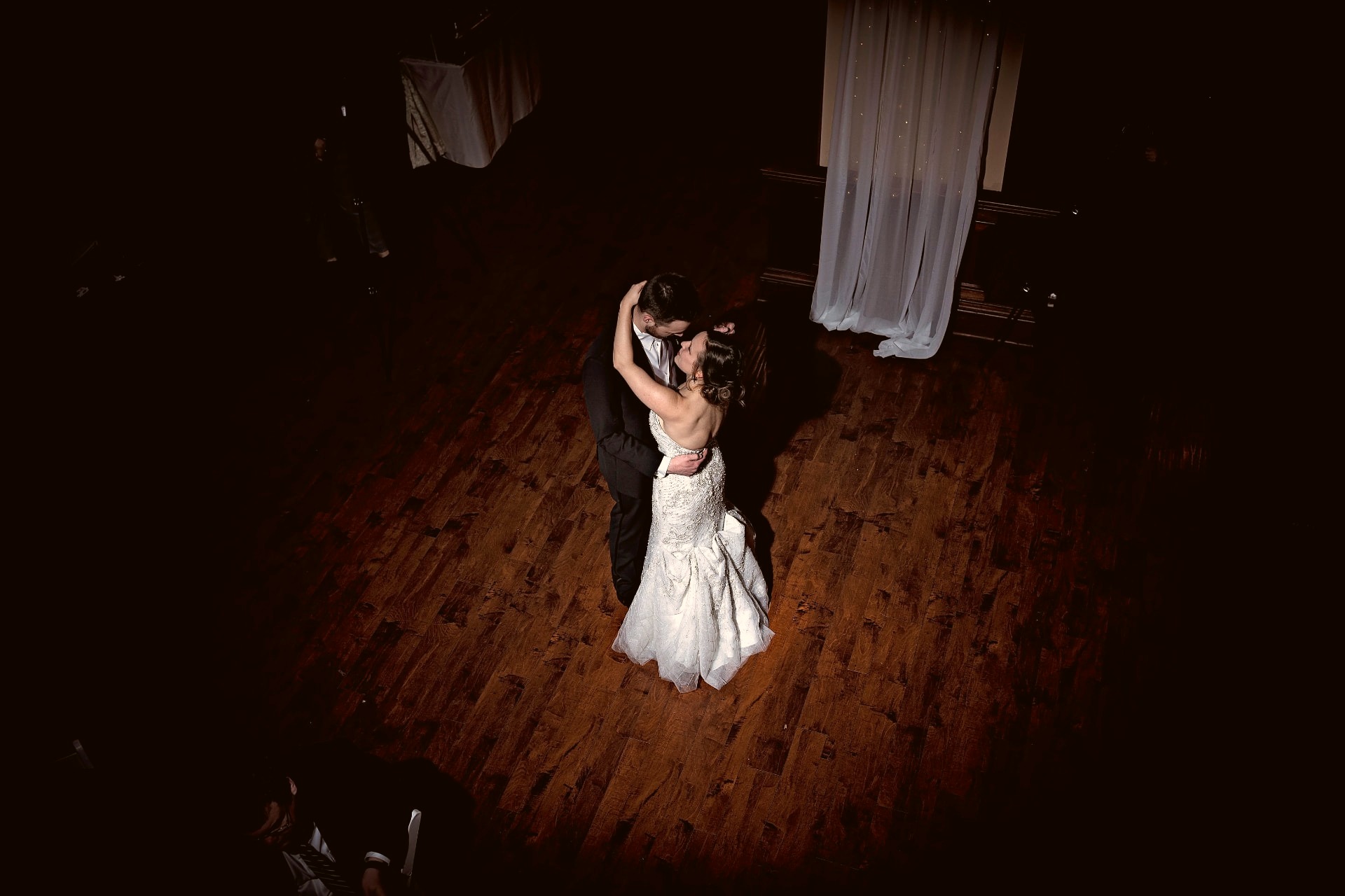 Bride and groom sharing their first dance, seen from above on a dark wooden floor