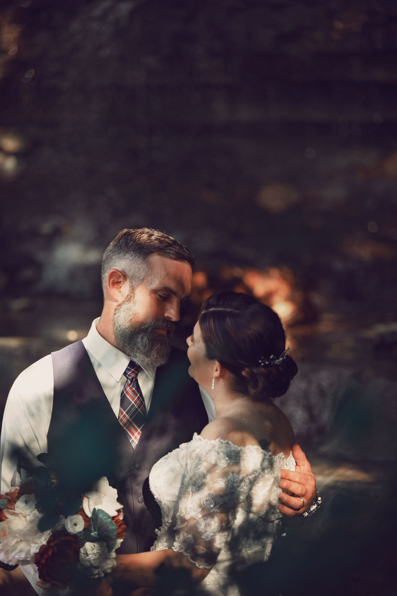 Bride and groom facing each other in a shaded forest