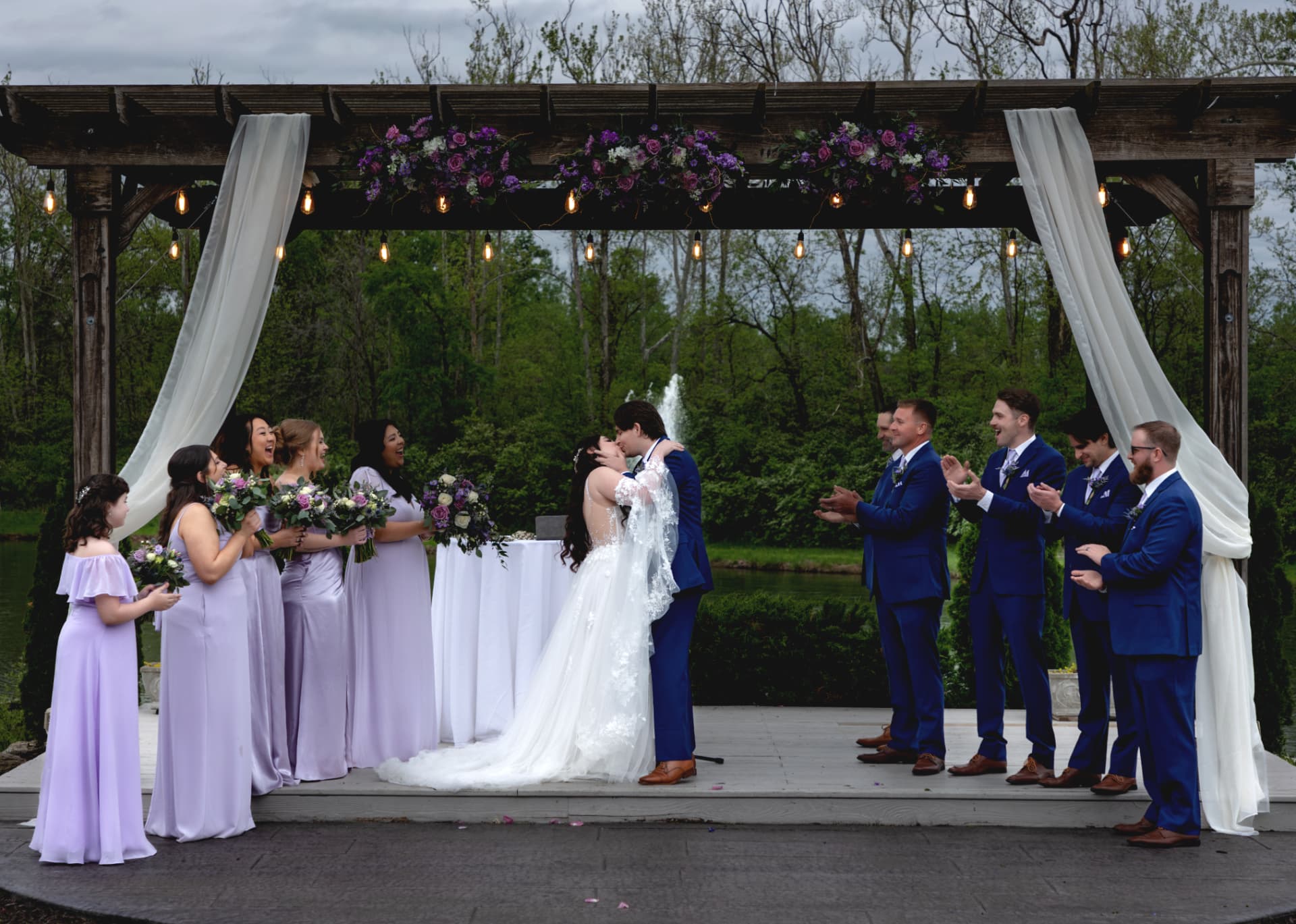 Wide view of the ceremony under a flower-covered pavilion