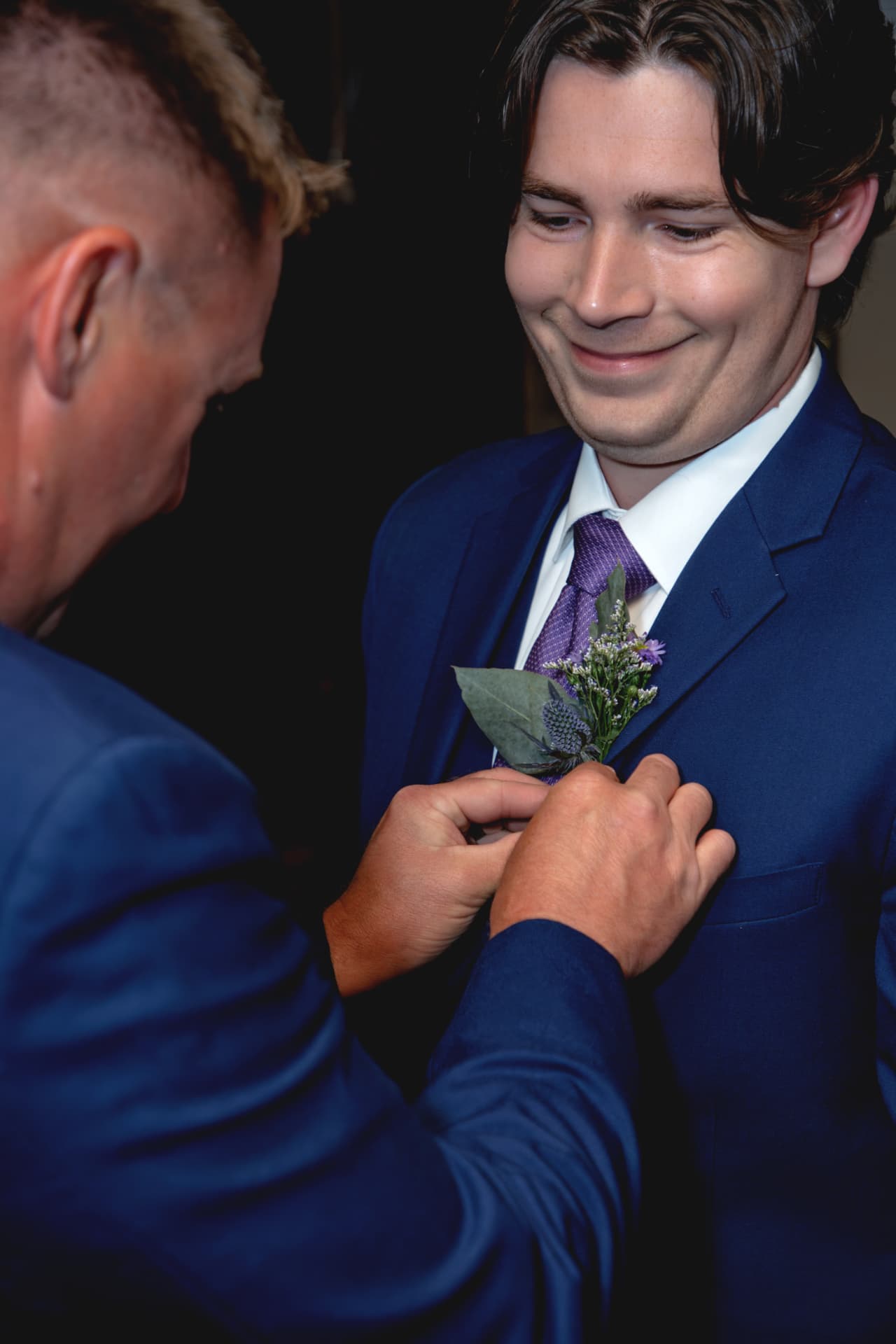 A boutonniere being pinned to Tristan’s blue suit