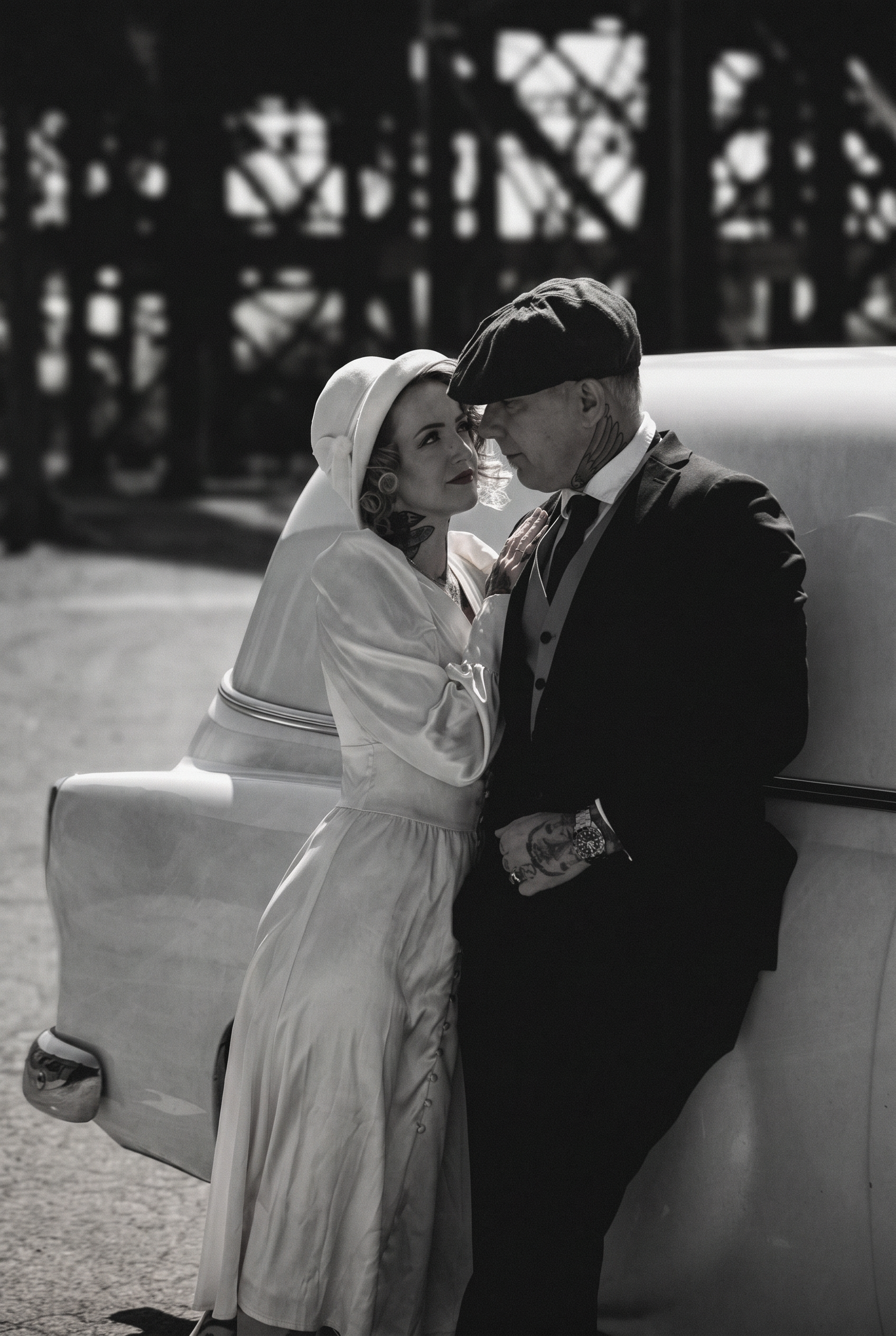 Bride and groom beside a vintage car in black and white