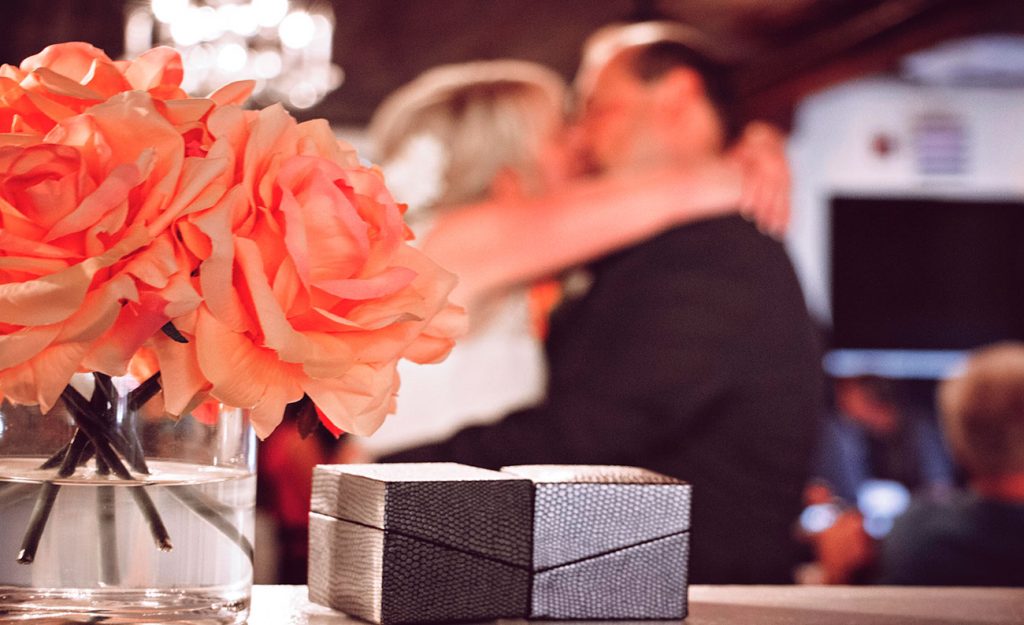 Close up view of wedding band box with couple kissing in background