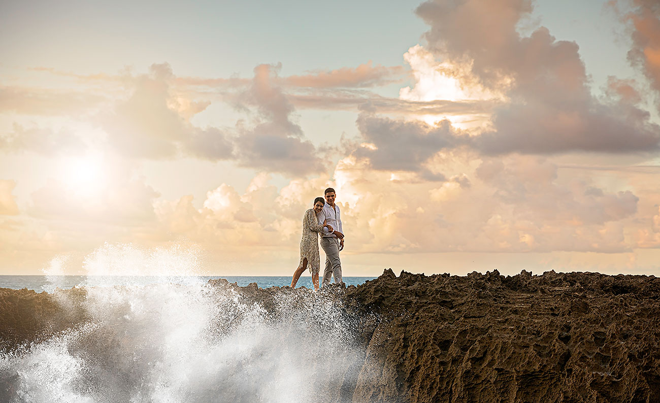 wedding couple on rocks with ocean and sunset